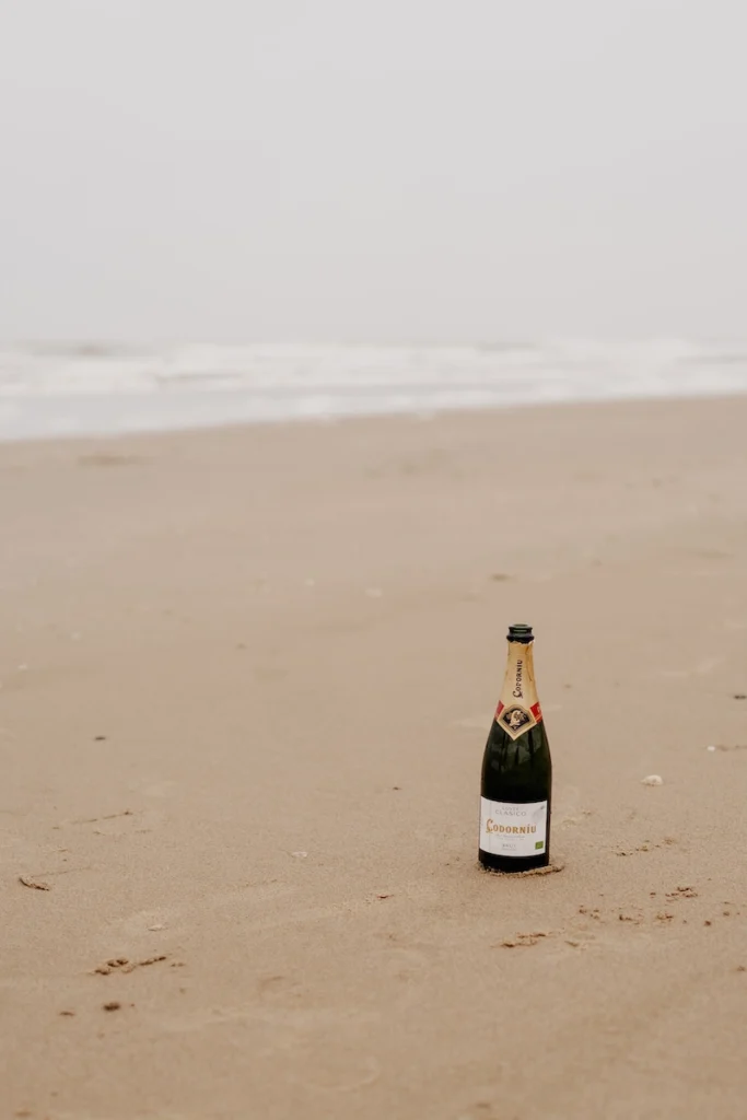 Champagnerflasche steht einsam am Strand, bereit für Feierlichkeiten.
