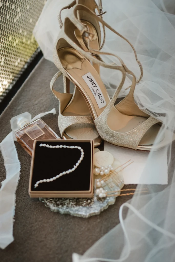 Hochzeitsaccessoires: Schuhe und Schmuck auf einem Tisch arrangiert.