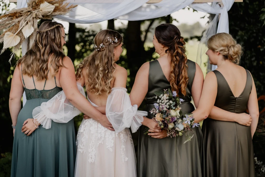 Braut und Brautjungfer von hinten, elegant mit Blumen im Haar.
