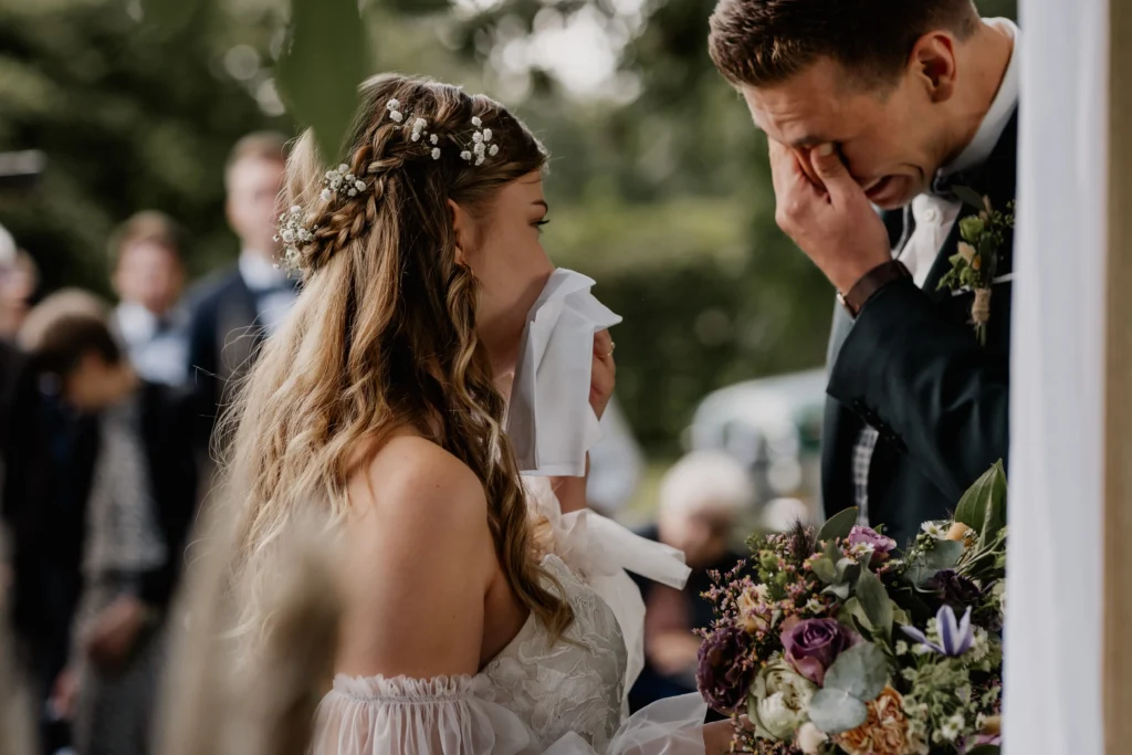 Nahaufnahme der Braut während der Zeremonie, emotional mit Taschentuch.
